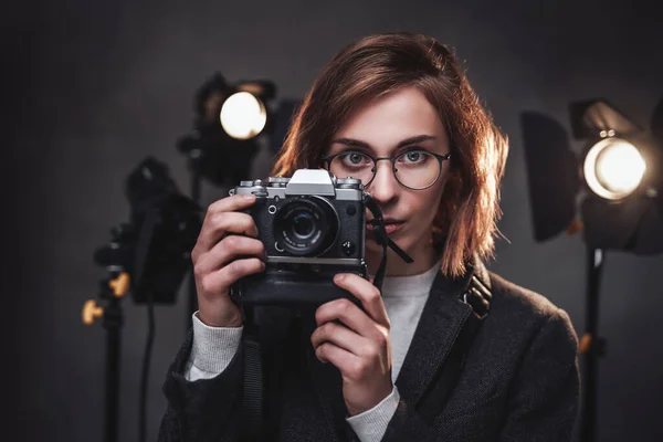 Hermosa pelirroja fotógrafa mujer sostiene una cámara digital y mirando a la cámara —  Fotos de Stock