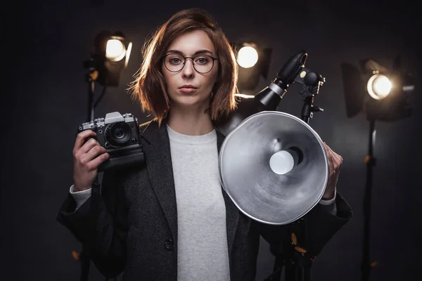 Vacker rödhårig kvinnlig fotograf håller en digitalkamera och tittar på kameran — Stockfoto