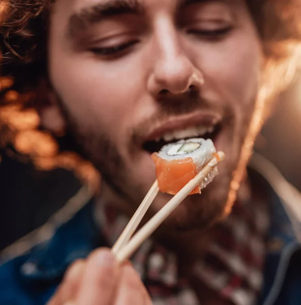 Gros portrait d'un bel homme mangeant des sushis — Photo