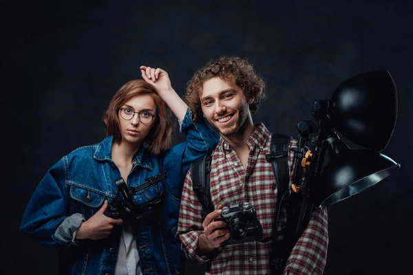 Zespół dwóch młodych fotografów posiada aparat cyfrowy i sprzęt oświetleniowy w studio — Zdjęcie stockowe