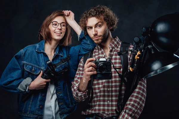 A equipe de dois jovens fotógrafos detém uma câmera digital e equipamentos de iluminação em estúdio — Fotografia de Stock