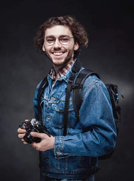 Portrét pohledného mladého fotografa s kudrnatými vlasy v džínové bundě drží fotoaparát — Stock fotografie
