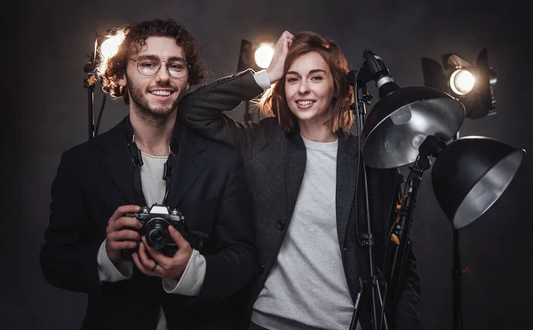 El equipo de dos fotógrafos sostiene una cámara digital y un equipo de iluminación posando en el estudio —  Fotos de Stock