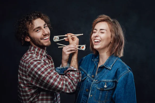 Joven pareja en amor comer sushi en bruderschaft tener divertido juntos en oscuro estudio — Foto de Stock