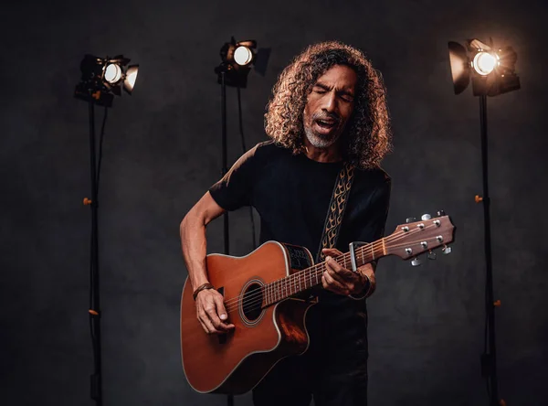 Middelbare Spaanse muzikant in zwart t-shirt emotioneel zingend en gitaar spelend — Stockfoto