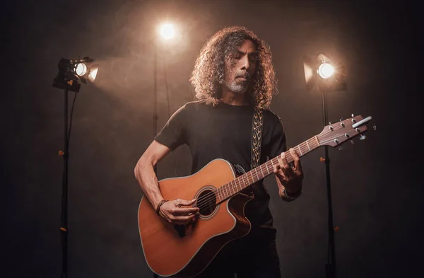 Musicien hispanique talentueux jouant de la guitare dans les lumières de scène — Photo