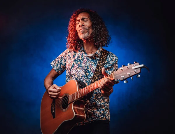 Talentvolle Spaanse muzikant in een Hawaïaans shirt gitaar spelen op een donkere — Stockfoto