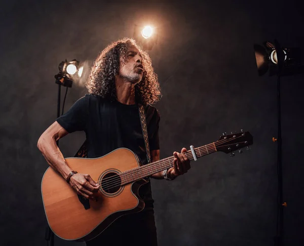 Siyah tişörtlü orta yaşlı İspanyol müzisyen duygusal olarak şarkı söylüyor ve gitar çalıyor. — Stok fotoğraf
