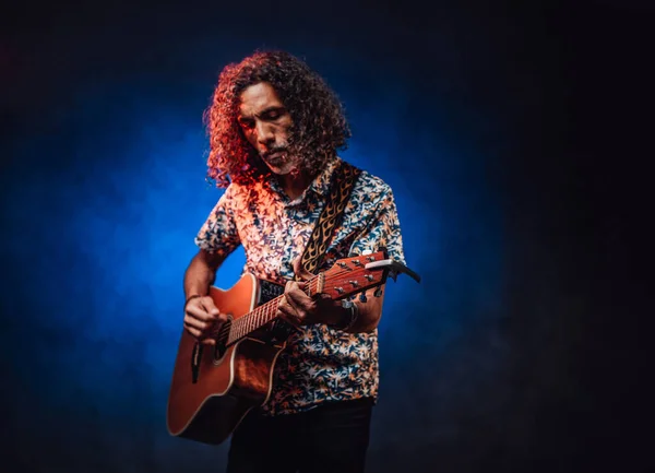 Talentoso músico hispânico com uma camisa havaiana tocando guitarra em um escuro — Fotografia de Stock
