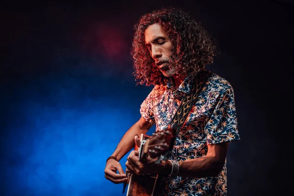 Músicos hispânicos de meia-idade tocando guitarra em um escuro iluminado por luz azul e vermelha — Fotografia de Stock