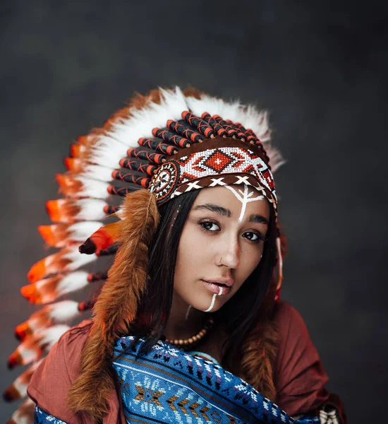 Close up portrait of a attractive young American Indian woman with make up in traditional feather hat and clothes — Stock Photo, Image