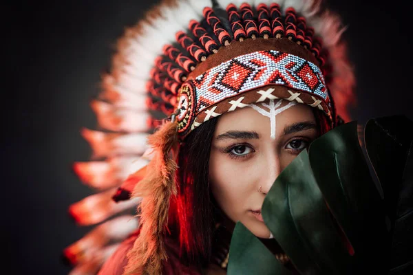 Mooie jonge Amerikaanse Indiaanse vrouw in etnisch kostuum houdt een groot groen tropisch blad — Stockfoto