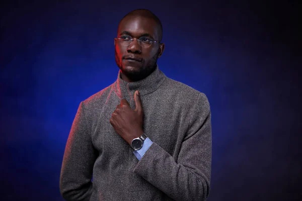 スタイリッシュなアフリカ系アメリカ人男性でグレーのジャケットと青の光と暗い背景の眼鏡 — ストック写真