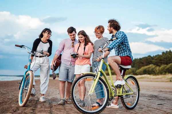 Fem glada vänner med sina cyklar på stranden — Stockfoto