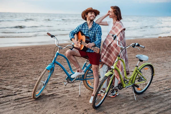 Vackra par på stranden med sina blå och gröna cyklar, tittar på varandra — Stockfoto