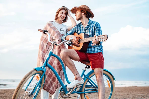 Två attraktiva människor står med sin cykel och en gitarr. Båda ler mot varandra. — Stockfoto