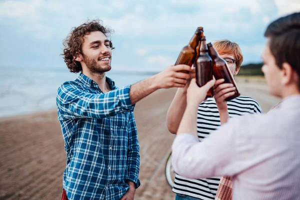 Eine Gruppe glücklicher Kumpels, die ihre Freizeit am Strand verbringen, Bier trinken und Spaß haben — Stockfoto
