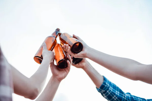 Freunde heben und klirren ihre braunen Flaschen mit Bier — Stockfoto