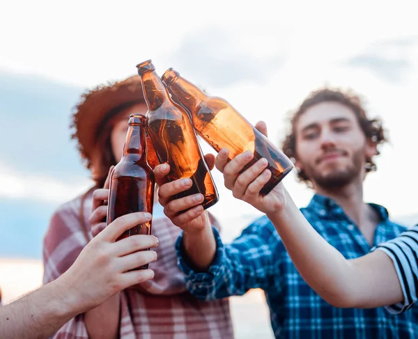 Eine Gruppe fröhlicher Freunde klirrt mit ihren Bierflaschen — Stockfoto