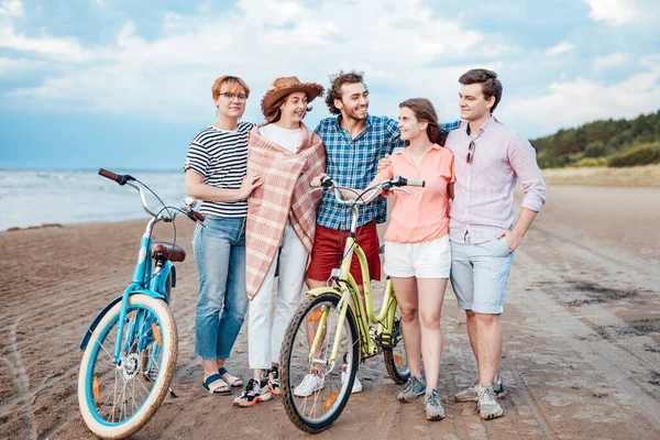 Fem vänner på stranden med sina cyklar, kramar varandra — Stockfoto