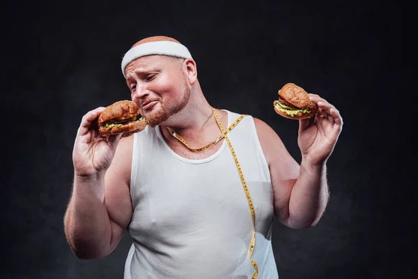 Dicker Mann spielt mit zwei Hamburgern in der Hand — Stockfoto