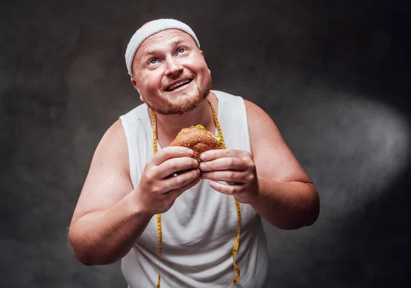 Mohutní muži se dívají na světlo s hamburgerem v ruce — Stock fotografie
