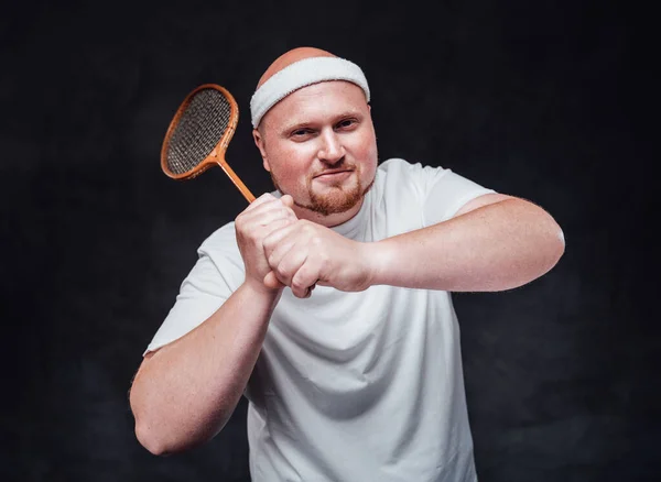 En man med röda kinder svingar en badminton racket — Stockfoto