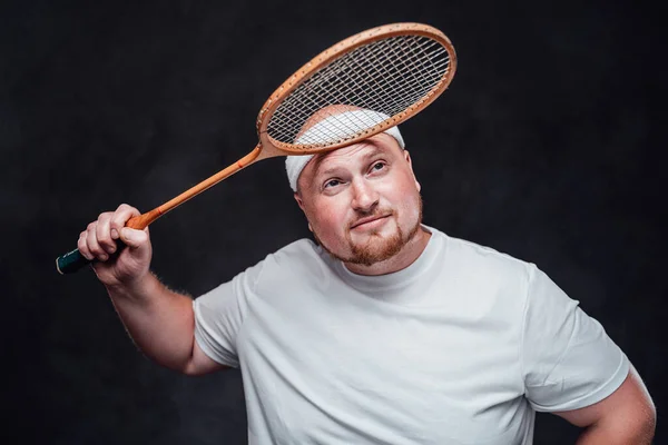 Um homem gordo num fato desportivo tem uma raquete acima da cabeça. — Fotografia de Stock