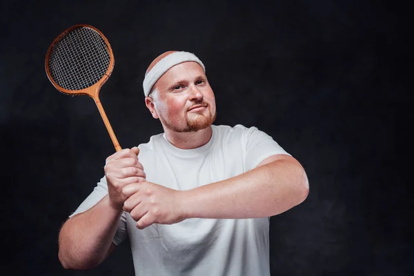 Djärv och fet man med röda kinder svingar en badminton raket — Stockfoto