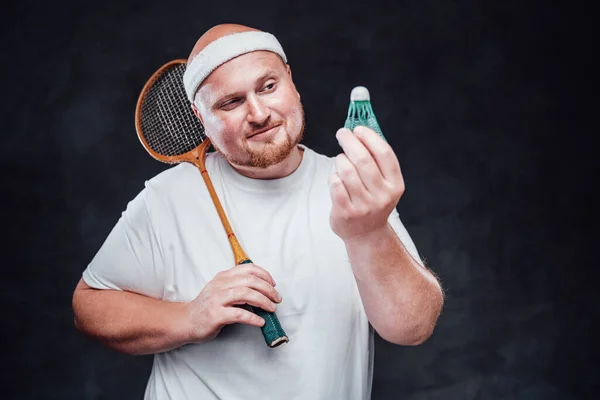 En skallig idrottsman med en badmintonraket i handen tittar på en skyttel — Stockfoto