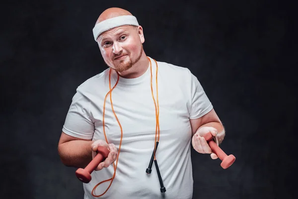 Толстяк в белой футболке с двумя гантелями в каждой руке и веревкой на шее — стоковое фото
