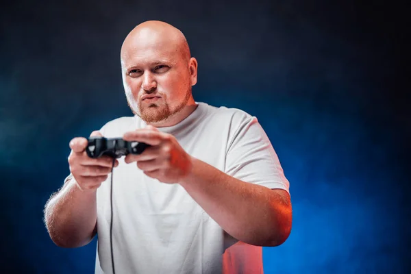 Jogador pudim em uma camiseta branca joga um console de jogo — Fotografia de Stock