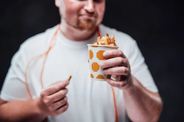 Homem com excesso de peso no sportswear comer batatas fritas — Fotografia de Stock
