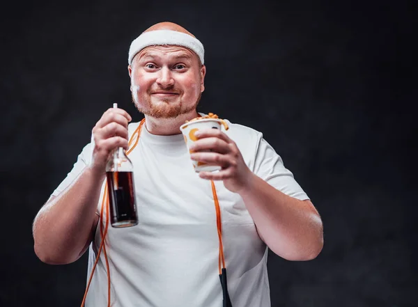 Homem careca sorridente em sportswear comer batatas fritas com cola de coca — Fotografia de Stock