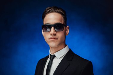 Yakışıklı ve başarılı. Siyah takım elbiseli ve güneş gözlüklü genç bir işadamının portresi.