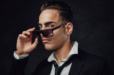 Yakışıklı ve başarılı. Siyah takım elbiseli ve güneş gözlüklü genç bir işadamının portresi.