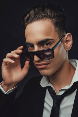 Yakışıklı ve başarılı. Siyah takım elbiseli ve güneş gözlüklü genç bir işadamının portresi.