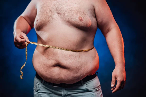 Zeer dikke man pronkt en meet zijn enorme buik — Stockfoto