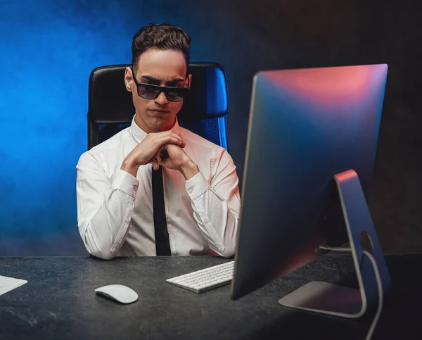 Ofis masasında oturan beyaz gömlekli ve güneş gözlüklü kendinden emin genç iş adamı. — Stok fotoğraf