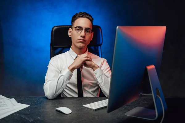 A young office worker in a white shirt and tie sits in the workplace — Stock Photo, Image