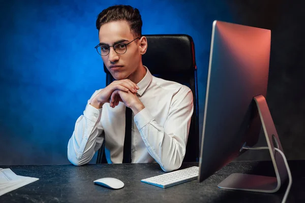 A young office worker in a white shirt and tie sits in the workplace — Stock Photo, Image