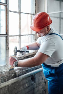 Müteahhit eski tuğla duvarları yıkmak için çekiç kullanıyor.