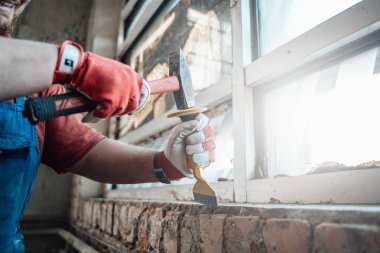İşçiler çekiç ve keskiyle güçlü eller, tuğla duvardaki alçıdan kurtulmak.