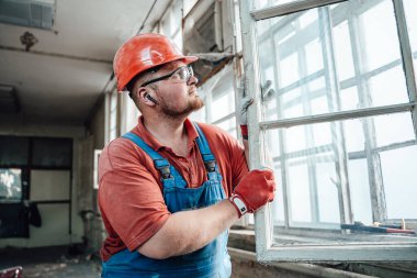 İnşaat alanında pencereyle çalışan kendine güvenen bir inşaatçı.