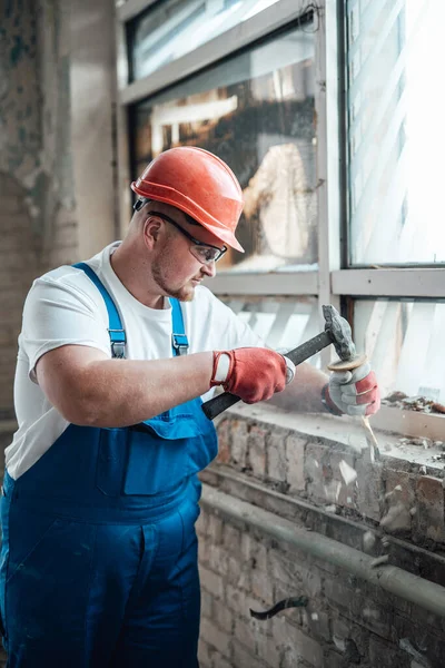 Robotnik budowlany pracujący młotkiem, niszczący stare ceglane ściany — Zdjęcie stockowe