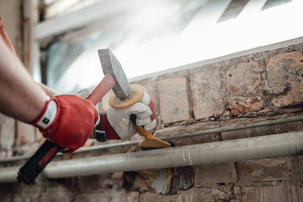 Builders strong hands working with hammer and chisel at the construction site