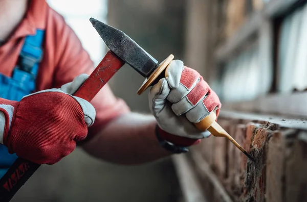 レンガの壁に石膏を取り除く、ハンマーとノミで労働者の強い手 — ストック写真