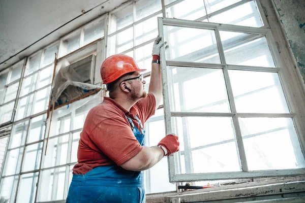 Büyük bir inşaat alanında penceresi olan şişman bir inşaatçı.