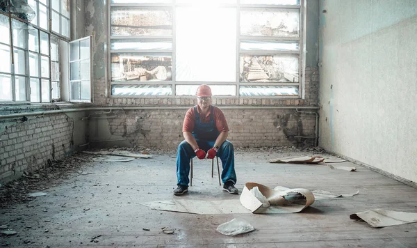 Werknemer zit op een stoel in het midden van een bouwplaats — Stockfoto