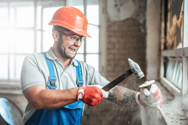 Builder strikes with a hammer, screaming — Stock Photo, Image